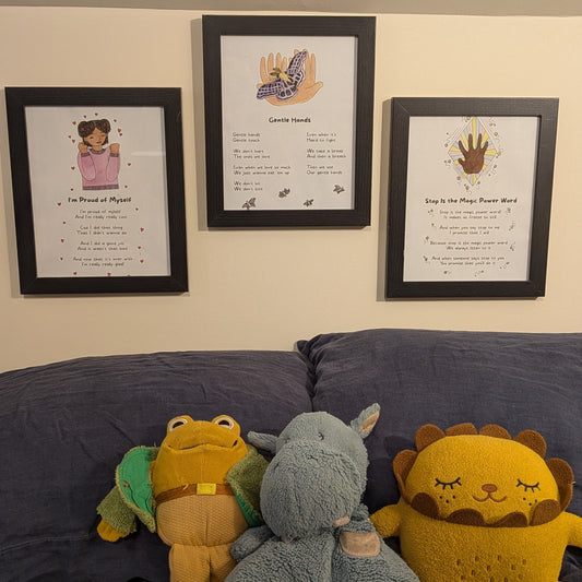 Three stuffed animals (a lion, a elephant, and a monkey) sitting on a couch with framed mama nous song lyric posters behind them.